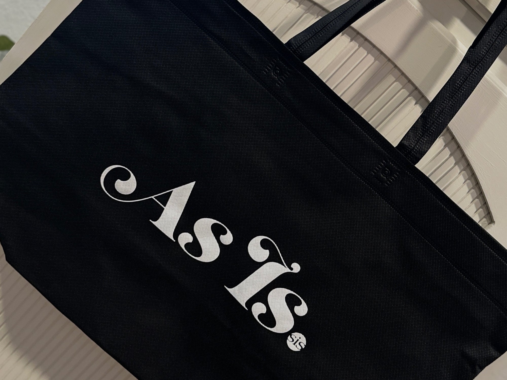 Black tote bag with ‘As Is’ logo, branded merchandise promoting self-acceptance and empowerment