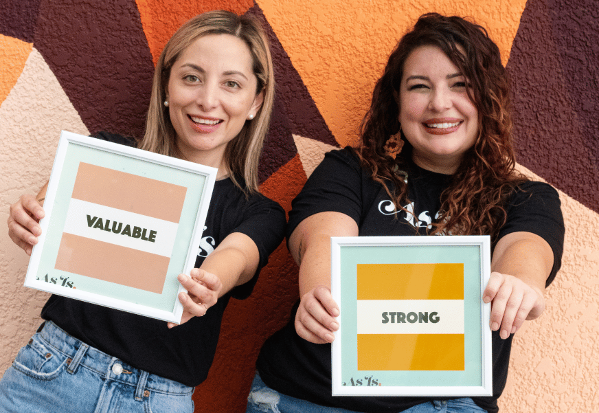 Two women holding motivational signs, self-love and empowerment message