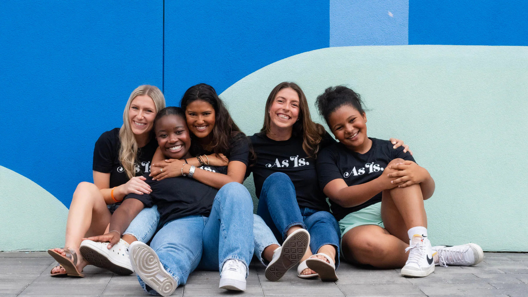 Diverse group of women sitting together smiling, celebrating friendship and empowerment in casual setting