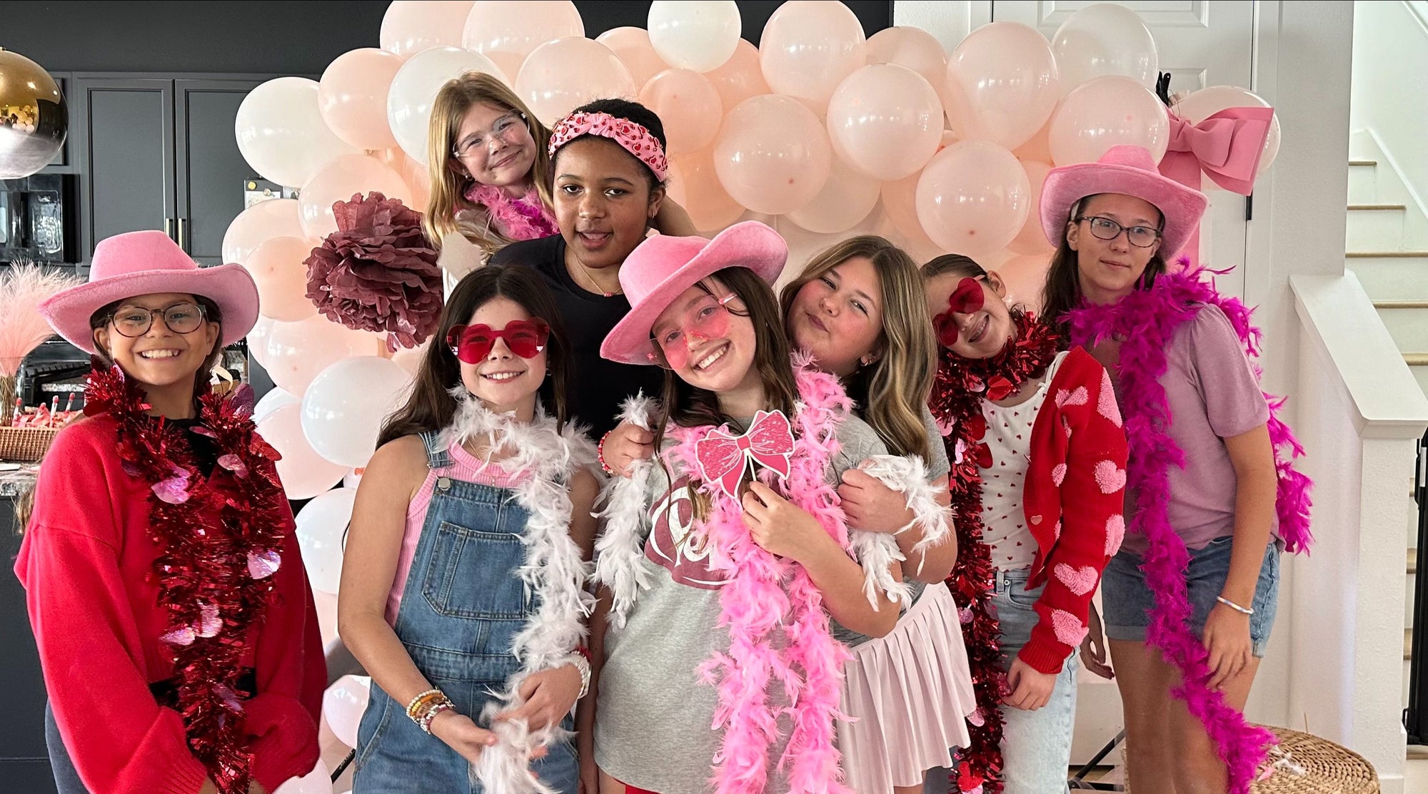 Young girls at fun dress-up party with pink boas and hats, joyful celebration and bonding moment